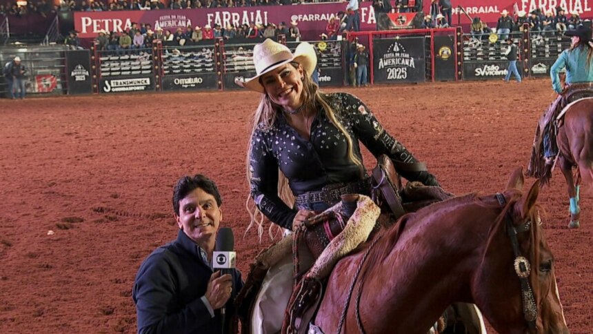 Um repórter de terno escuro, segurando um microfone com o logo da Globo, sorri para a câmera. Ao lado dele, uma mulher de chapéu de caubói e camisa preta bordada, sentada em um cavalo, também sorri. O fundo é uma arena de rodeio com público e banners no Globo Repórter