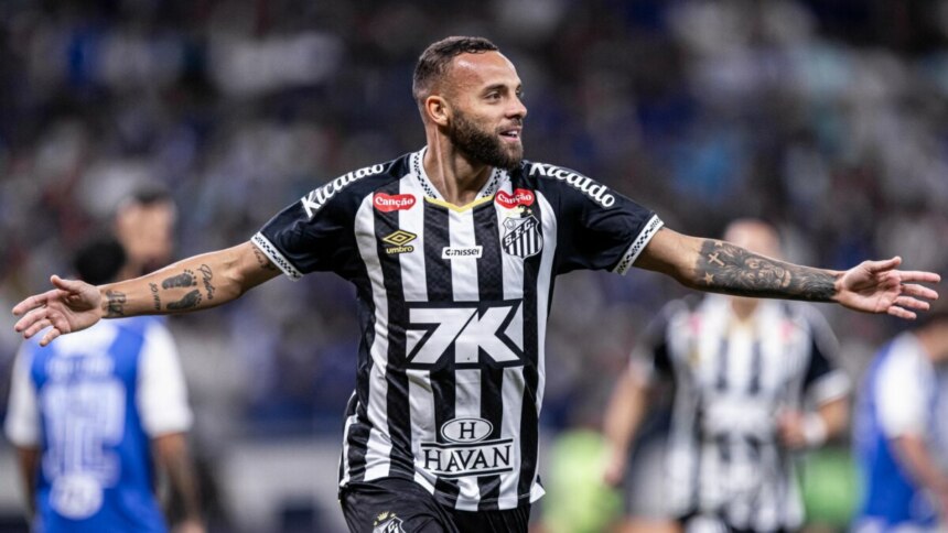 O jogador de futebol Guilherme, do Santos, comemora um gol com os braços abertos. Ele está no gramado, usando a camisa listrada preta e branca do time. Ele tem barba e tatuagens nos braços, e sorri enquanto olha para o lado. O nome do arquivo o associa a um gol em um jogo entre Santos e Cruzeiro.