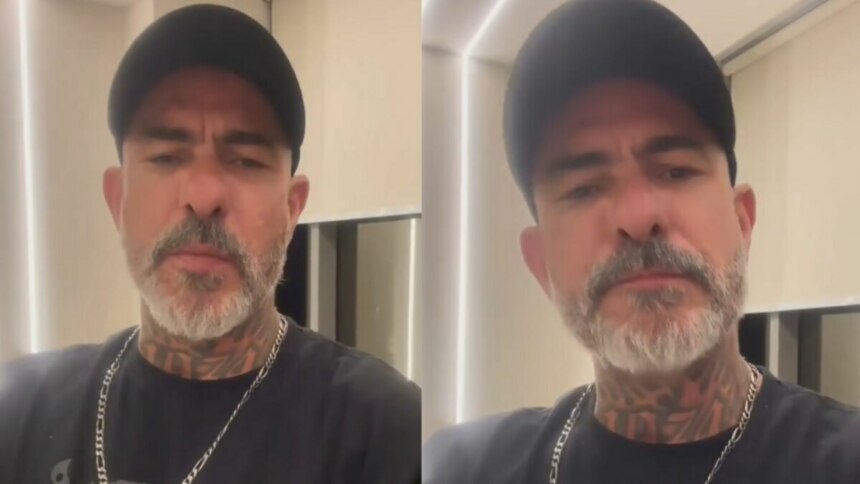 Montagem em tela dividida, com duas imagens iguais do chef Henrique Fogaça. Ele usa um boné preto, uma camiseta preta e exibe tatuagens no pescoço. Ele tem barba e bigode grisalhos e olha para a câmera com uma expressão séria, falando sobre o MasterChef Celebridades