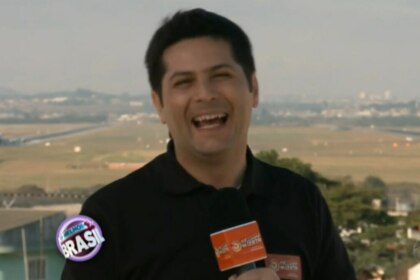 O repórter Humberto Ascencio, sorrindo e segurando um microfone em um ambiente externo. Ele está em um terraço com um fundo desfocado que mostra uma paisagem urbana com um campo e uma pista de aeroporto. Na parte inferior da tela, um logo do programa "O Melhor do Brasil" é visível.