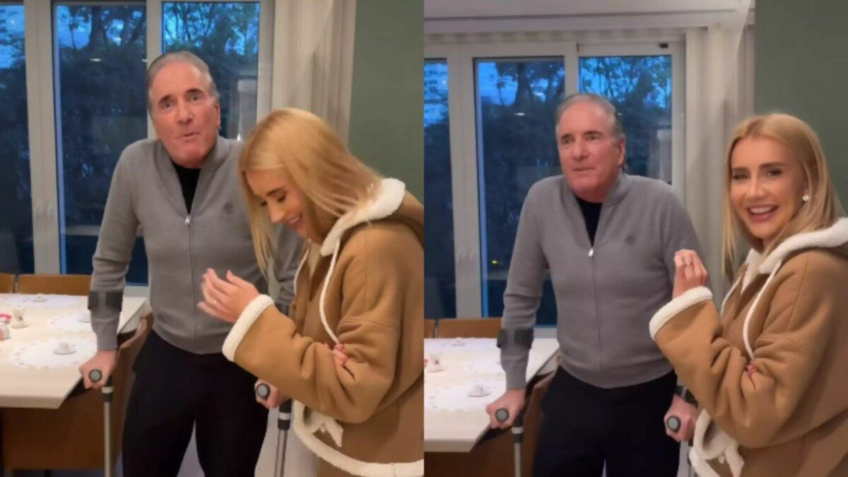 Montagem em tela dividida, com duas imagens do apresentador Roberto Justus e de uma mulher loira, que parece ser sua esposa. Ele está de muletas, usando um agasalho cinza. A mulher, de jaqueta marrom, sorri ao olhar para ele. Eles estão em uma sala de jantar.
