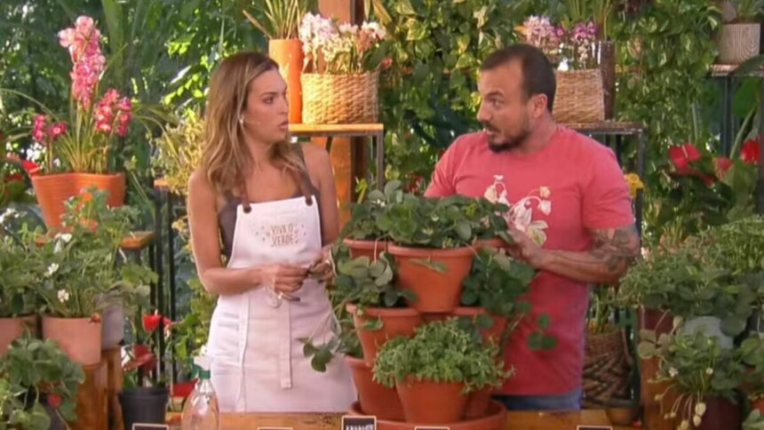 Talitha Morete e Murilo Soares no programa "É de Casa", com Talitha usando um avental e Murilo gesticulando em um cenário repleto de plantas.