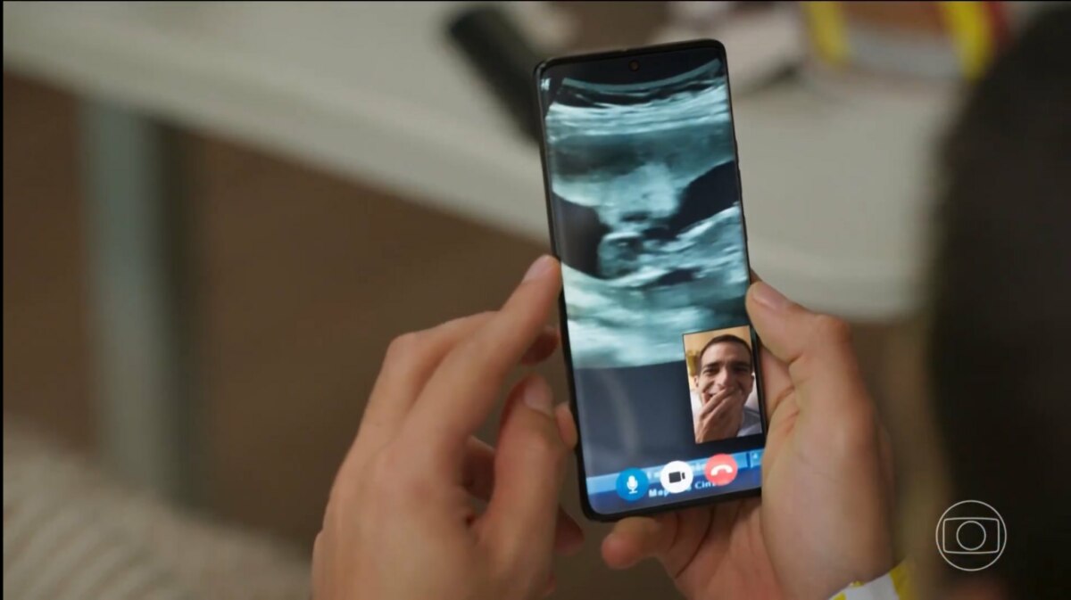 Afonso com três mãos, em trecho de chamada de vídeo por um celular, em cena de Vale Tudo