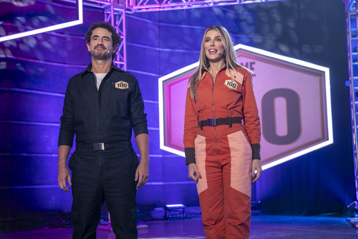 Felipe Andreoli e Rafa Brites no centro do palco do Game dos 100 olhando para o horizonte
