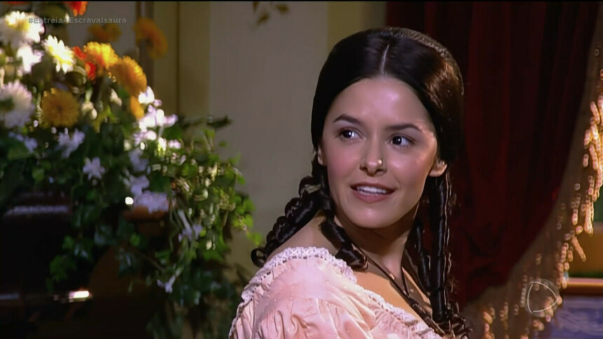 Isaura de vestido salmon toca piano na sala da fazenda em cena de A Escrava Isaura