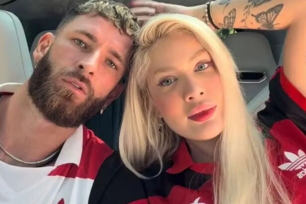 O jogador Léo Pereira, de barba, e a influenciadora Karoline Lima, de cabelo loiro, posam lado a lado em uma selfie. Ambos usam camisas do Flamengo.