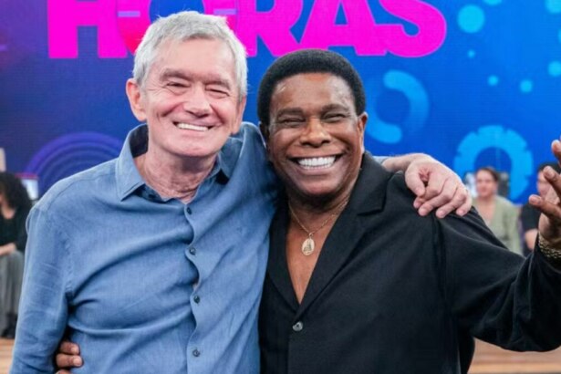 O apresentador Serginho Groisman e o cantor Luiz Carlos, do Raça Negra, abraçados e sorrindo no palco do programa Altas Horas.