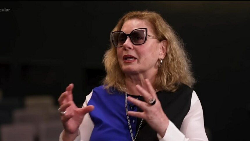 A atriz Vera Fischer, com cabelos loiros e ondulados, sorri para a câmera durante uma entrevista para o programa Domingo Espetacular.