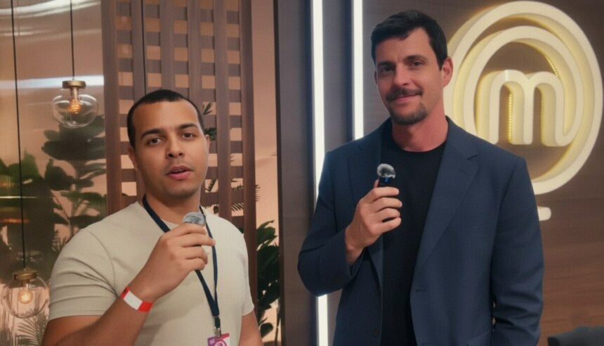 Repórter Matheus Canil do Portal Alta Definição segura microfone enquanto entrevista Felipe B. no cenário da final do MasterChef Brasil 2025