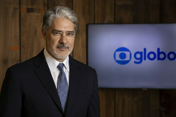 William Bonner sério em frente ao telão com o logo da TV Globo