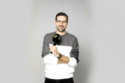 Paulo Mathias segurando o microfone do Link Podcast e sorrindo