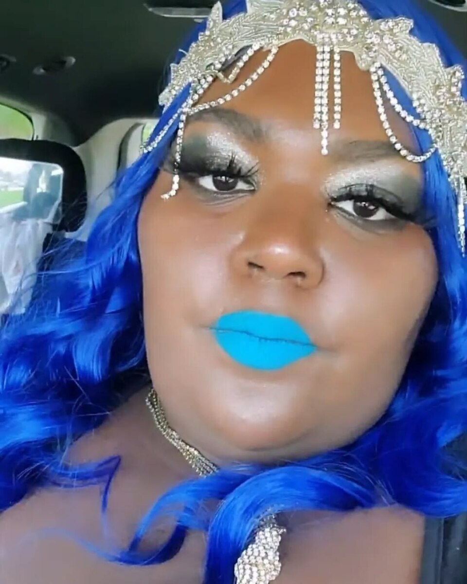 Shantel com cabelo azul vibrante, maquiagem marcante e adereço prateado, em cena impactante de Quilos Mortais
