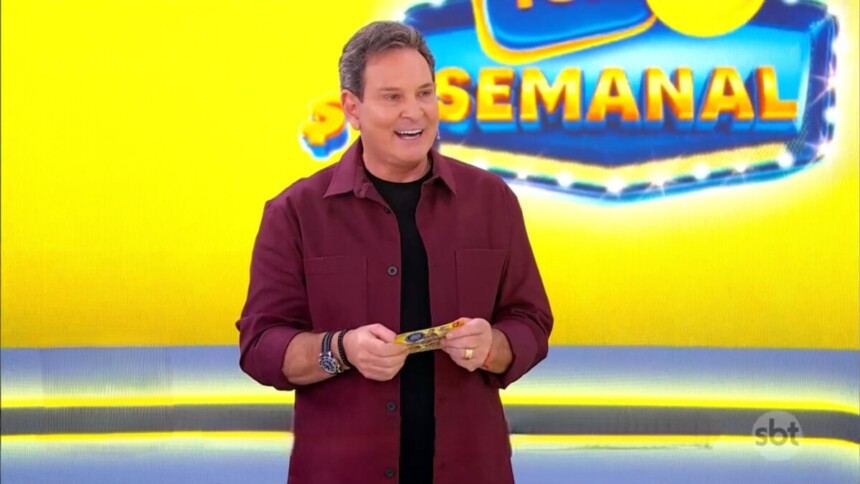 Luis Ricardo sorridente em frente ao telão da Tele Sena Semanal amarelo