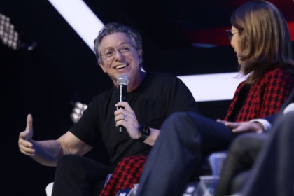 Boninho sorridente, ao lado de daniela beyruti e executivo na disney, em trecho da coletiva do the voice brasil