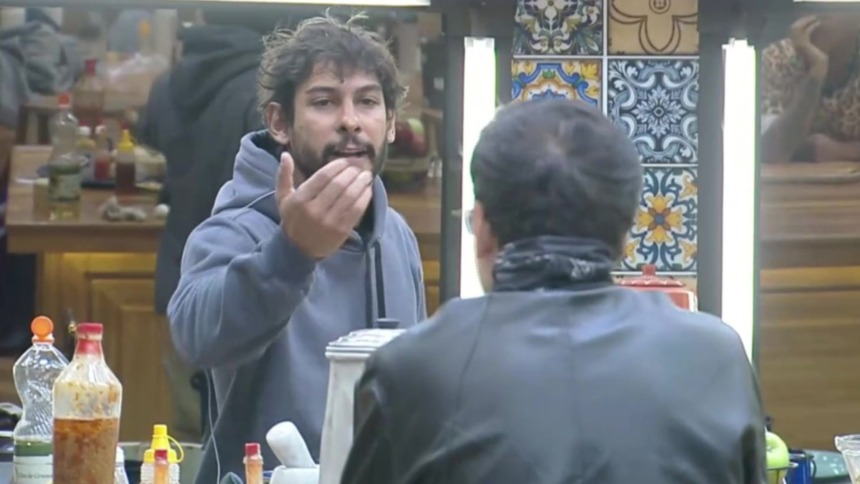 Shia (em pé) e Dudu Camargo (sentado) em trecho de treta na cozinha de A Fazenda
