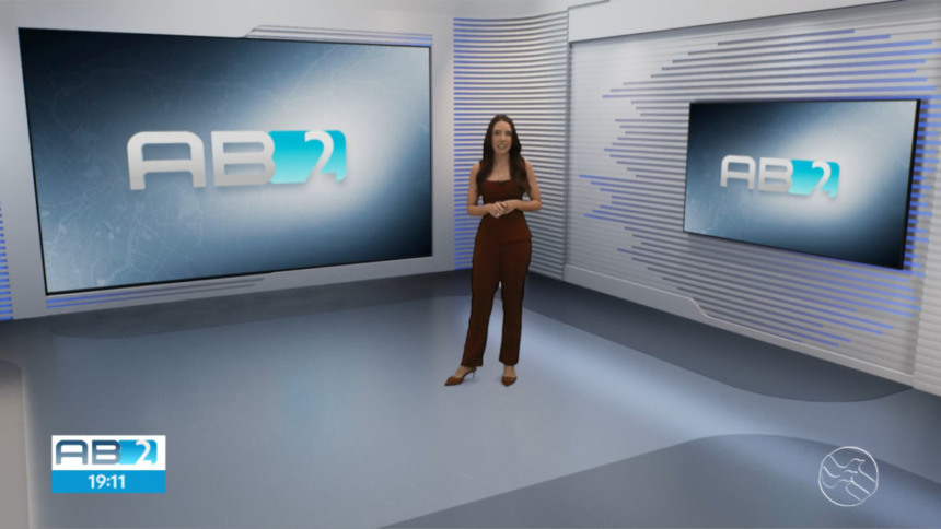 Nathalia Lopes no centro do cenário virtual do AB2, da TV Asa Branca Alagoas, que mostra falhas de recorte na roupa da apresentadora com uma mancha branca