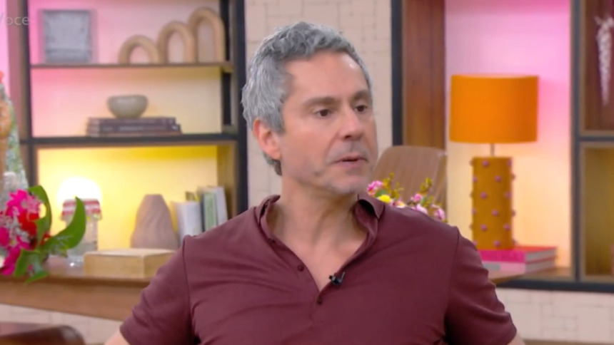 O ator Alexandre Nero, de cabelos grisalhos, em entrevista no cenário colorido do programa Mais Você. Ele veste uma camisa polo vinho.