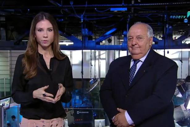 Amanda Klein de blusa preta ao lado de um comentarista de terno no estúdio do RedeTV! News no dia em que virou meme
