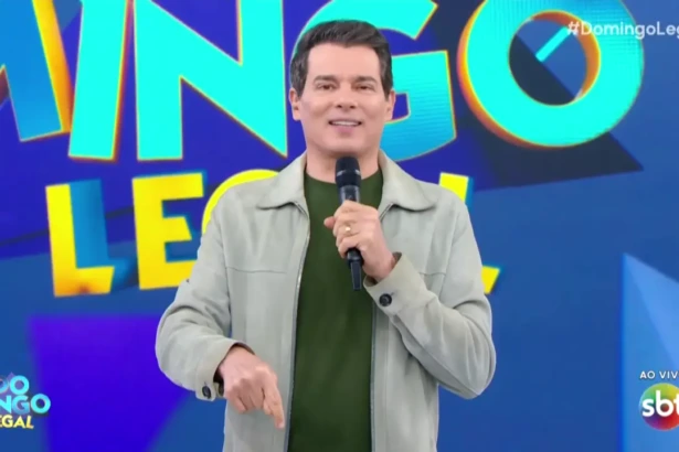 Celso Portiolli apresentando o Domingo Legal e sorrindo apontando para baixo