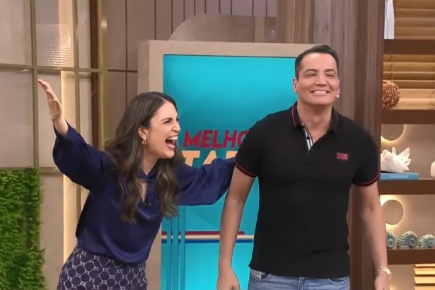 Chris Flores abre os braços e sorrir ao lado de Leo Dias no cenário do Melhor da Tarde