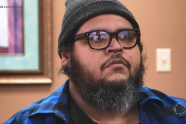 Dominic Hernandez no reality Quilos Mortais da Record, usando gorro cinza e camisa xadrez