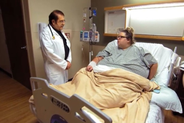 Dr. Now, em pé, e Brianne, deitada em um leito de hospital, em trecho de episódio do programa Quilos Mortais