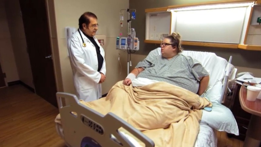 Dr. Now, em pé, e Brianne, deitada em um leito de hospital, em trecho de episódio do programa Quilos Mortais