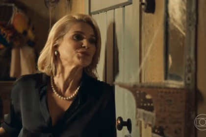 Sandra (Flavia Alessandra) atrás de uma porta sorrindo em cena de Êta Mundo Melhor!