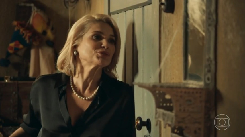 Sandra (Flavia Alessandra) atrás de uma porta sorrindo em cena de Êta Mundo Melhor!