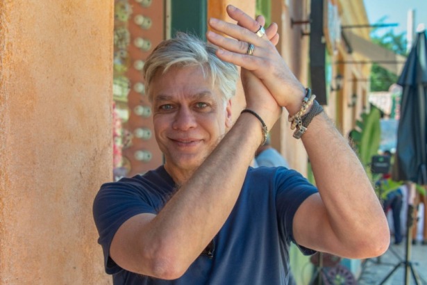 Ator Fabio Assunção, sorridente e gesticulando com as mãos no alto