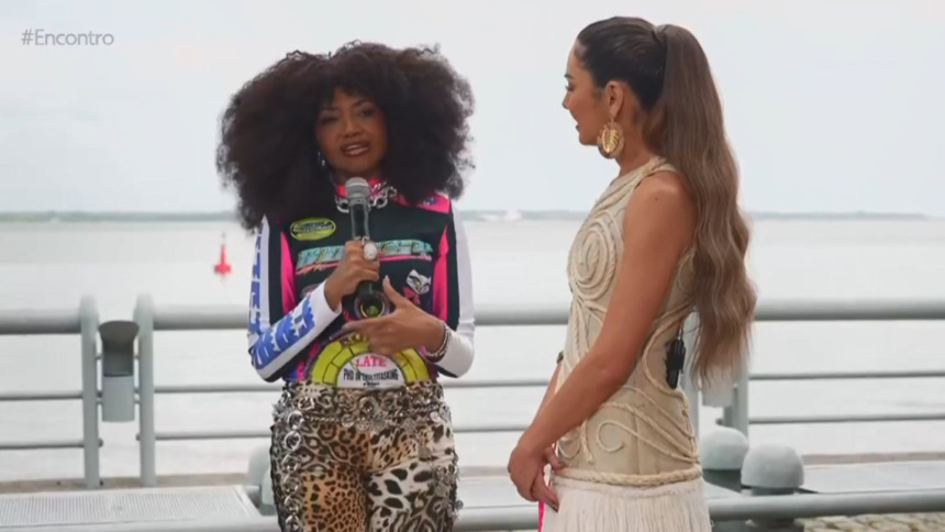 Gaby Amarantos (jaqueta racer, estampa de onça) em entrevista com Patrícia Poeta (vestido bege trançado) ao ar livre no Encontro de Belém.