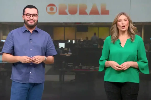 Pedro Málaga de camisa lilás ao lado de Cristina Vieira de blusa verde, os dois estão em pé na redação do Globo Rural