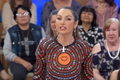 Patrícia Poeta vestida com a blusa do Criança Esperança em frente a plateia no palco do Encontro