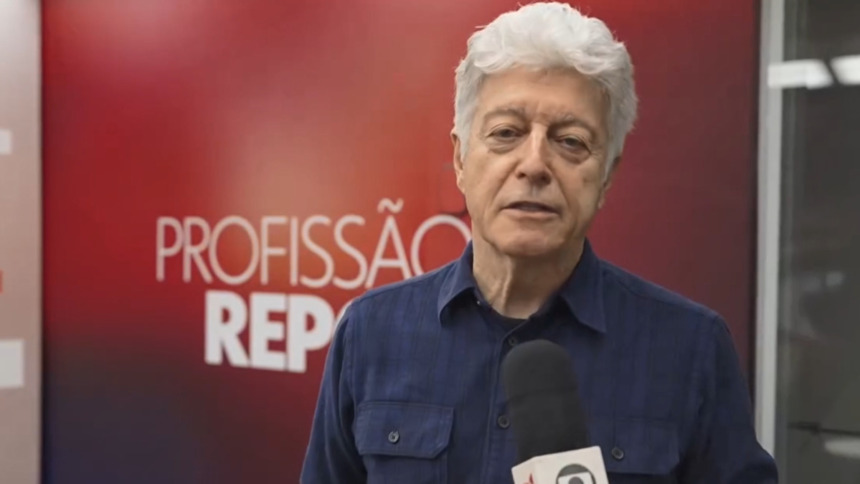 Caco Barcellos, em trecho do Profissão Repórter gravado na rua. Ele segura o microfone com a logo da emissora.