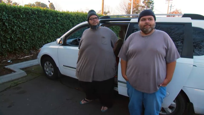 Dominic Hernandez e outro participante de Quilos Mortais em frente a uma van branca durante gravações do reality show