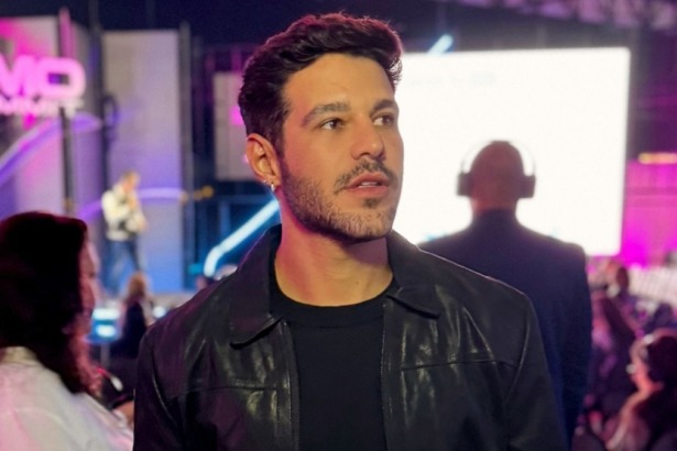 Rodrigo Mussi em foto posada, nos bastidores de um evento e com luzes ao fundo