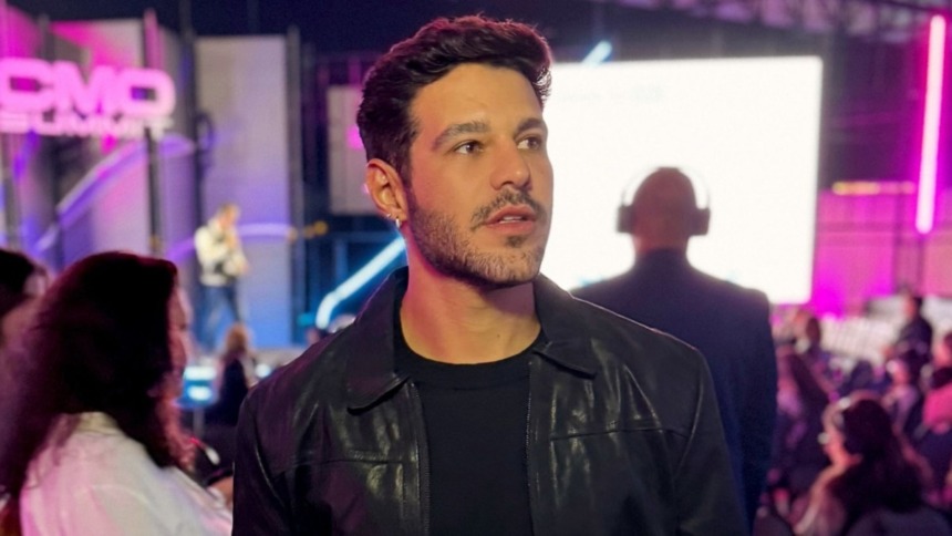 Rodrigo Mussi em foto posada, nos bastidores de um evento e com luzes ao fundo