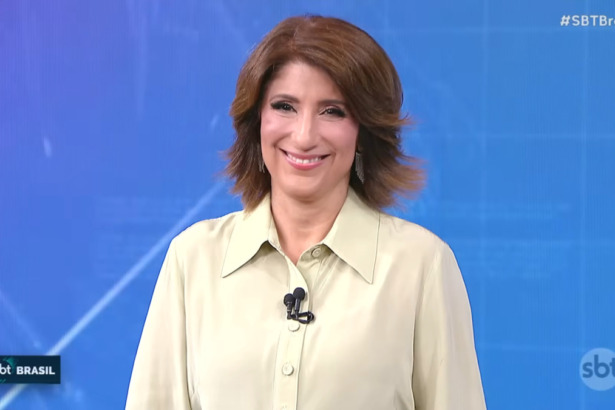 Simone Queiroz sorrindo no centro do cenário do SBT Brasil