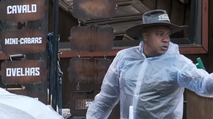 Toninho com capa de chuva e chapéu de fazendeiro apontando para os peões durante delegação em A Fazenda 17