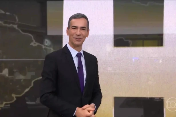 Cesar Tralli sorrindo em frente ao telão do Jornal Hoje no último dia de apresentação