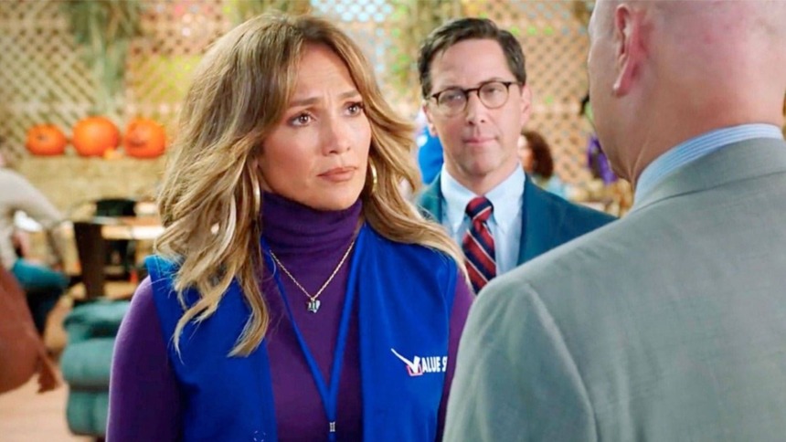 Cena do filme Uma Nova Chance. Jennifer Lopez usa um colete de trabalho azul e blusa roxa, olhando com expressão séria.