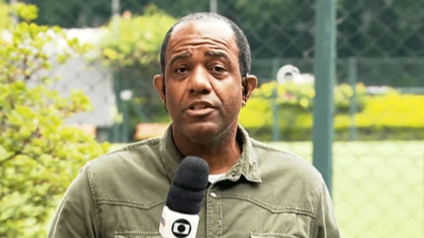 Abel Neto segurando o microfone da Globo em trecho de reportagem