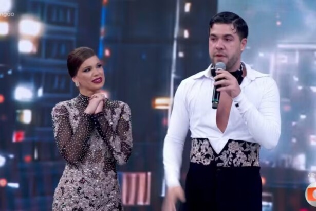 O influenciador Alvaro e a bailarina Mariana Torres no palco do Dança dos Famosos, com Alvaro falando ao microfone e visivelmente emocionado após apresentação