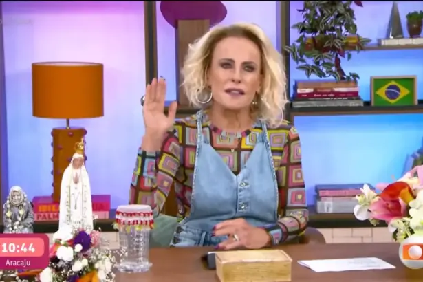 Ana Maria Braga levanta a mão esquerda enquanto apresenta o Mais Você sentada na bancada