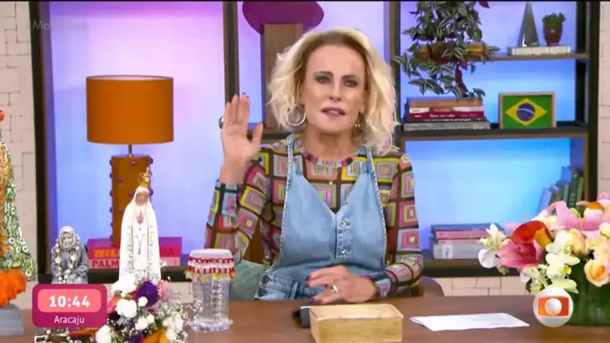Ana Maria Braga levanta a mão esquerda enquanto apresenta o Mais Você sentada na bancada