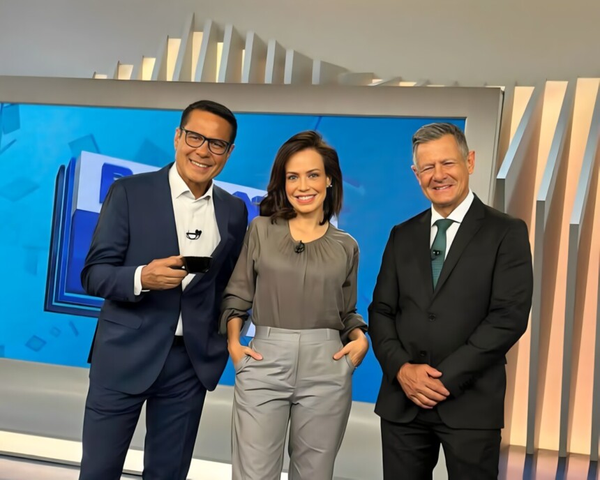 Willian Leite, Fabiana Oliveira e Comandante Lucca em pé em frente ao telão do Balanço Geral Manhã, ambos sorriem
