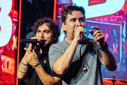 Dupla sertaneja Bruninho e Davi performando em show com cenário de luzes e grande público