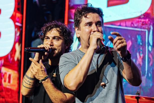 Dupla sertaneja Bruninho e Davi performando em show com cenário de luzes e grande público