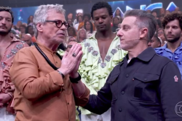 Carlinhos de Jesus e Luciano Huck em pé, em frente a plateia, durante a Dança dos Famosos no Domingão