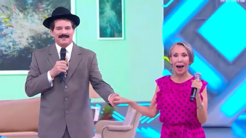 Celso Portiolli de Professor Girafales segura mão de Florinda Meza no cenário do Domingo Legal